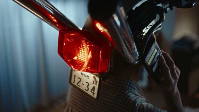 後ろ姿で、頭のバイクの赤いテールランプが点灯する場面